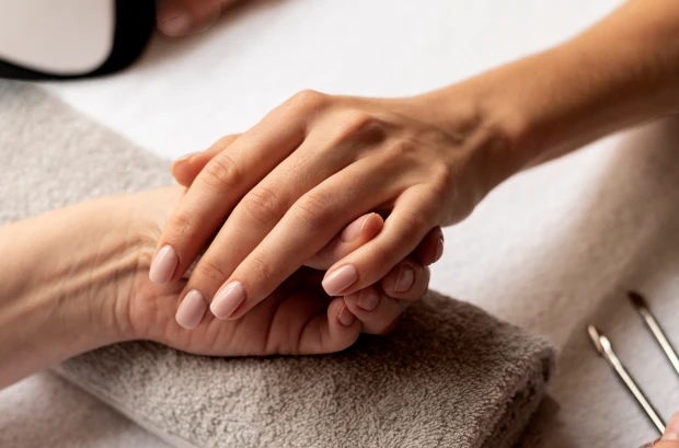 Mano che sorregge una mano di una cliente che effettua un manicure